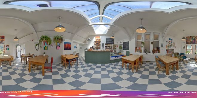 The vaulted glass-roofed cafe room with chequerboard floor and wooden tables