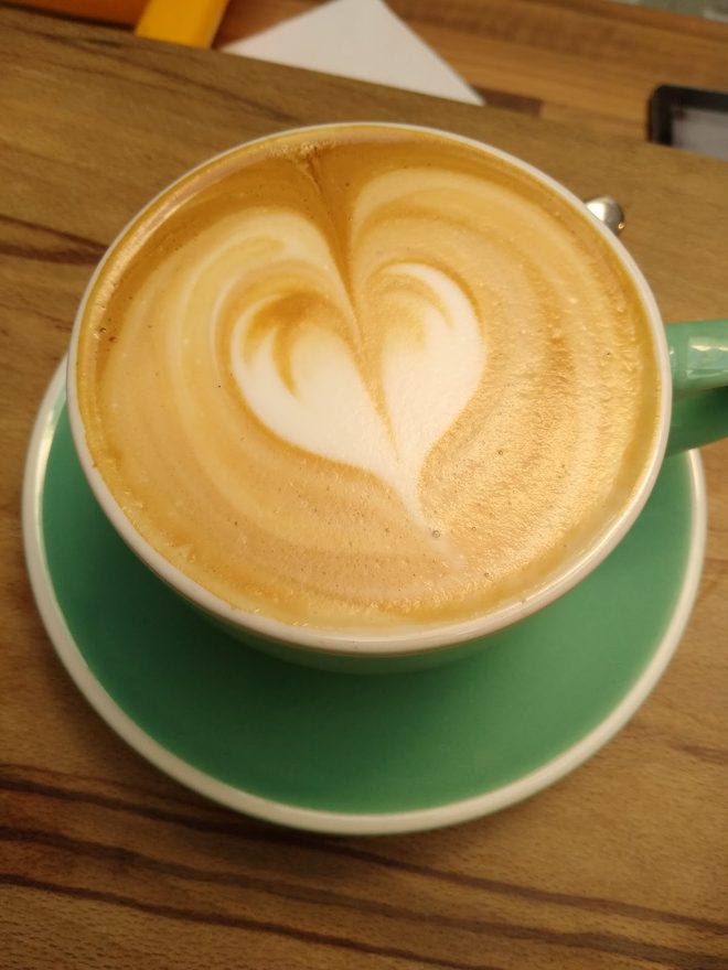 Latte art seen from above in a green cup and saucer