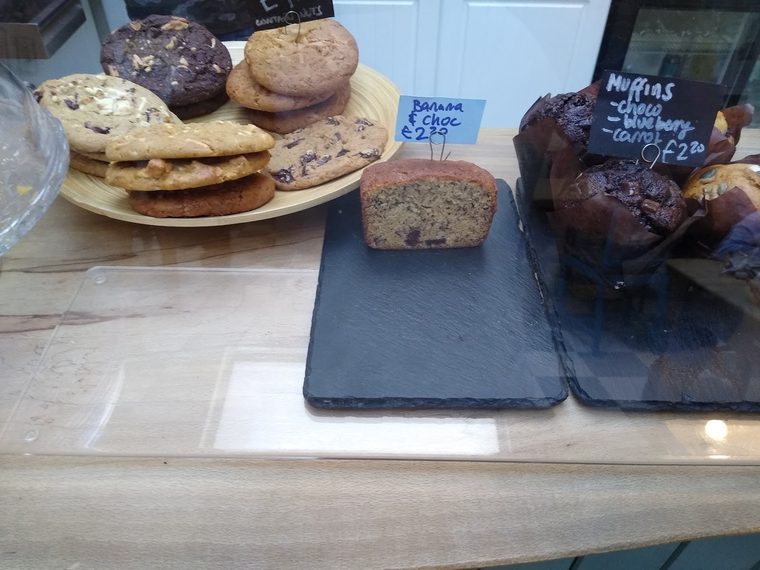 Blueberry muffins and a slice of banana chocolate loaf on a wooden table